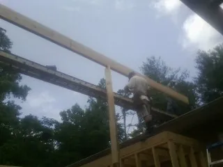 Carpenter setting a ridge beam over a new addition frame — Ice Dam Removal by Roofing Brothers in Gray Summit