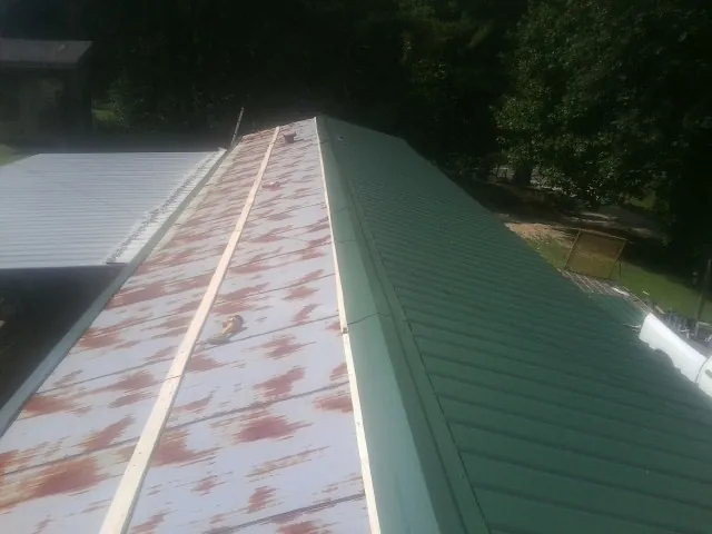 Old rusted panels beside newly installed green metal roofing — Wind Damage Roof Repair by Roofing Brothers in Gray Summit