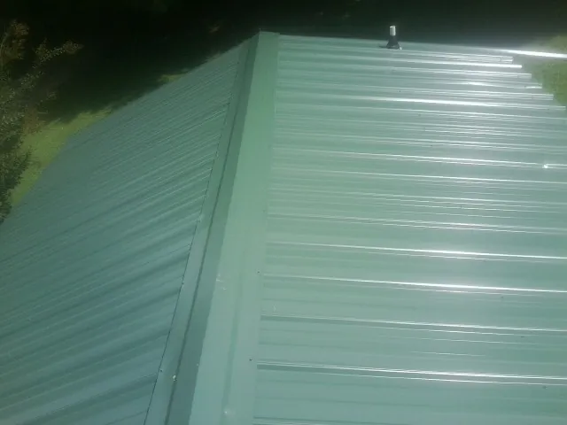 New green metal panels meeting at the ridge of a roof — Flat Roof Repair work by our crew in Gray Summit