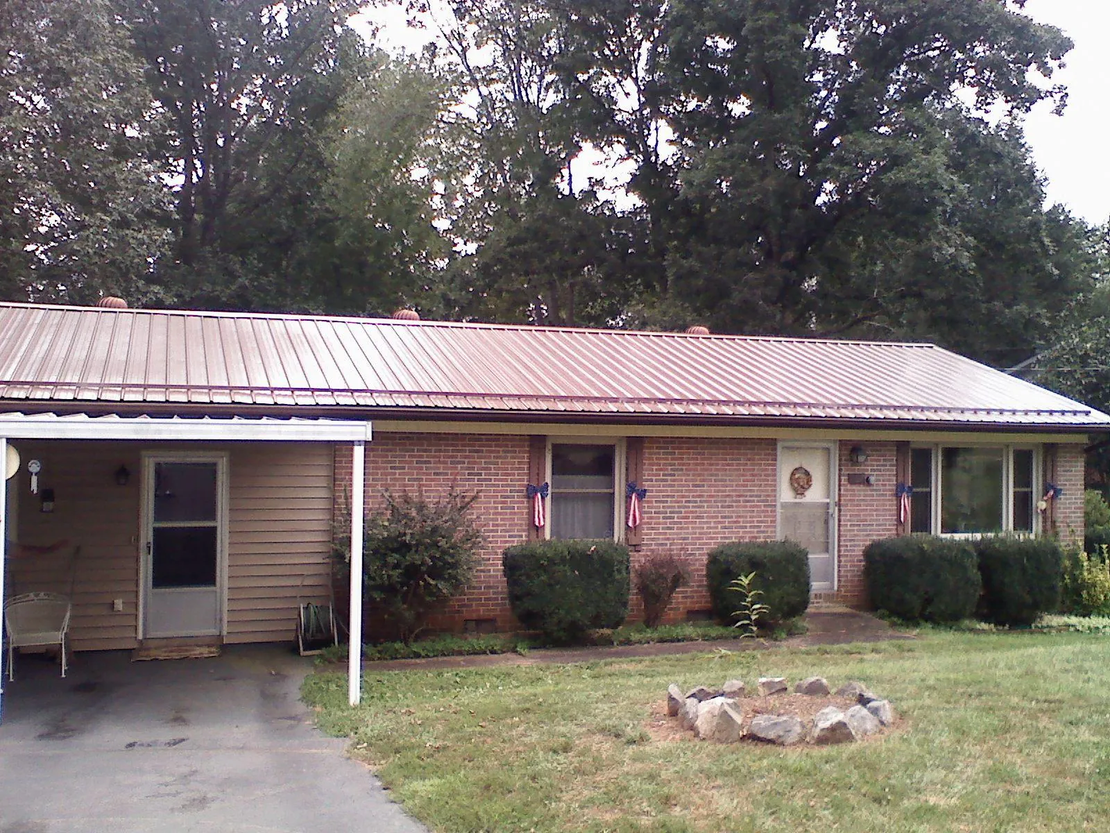 Bronze metal roof and carport on a brick ranch home — Roof Repair work by our crew in Gray Summit